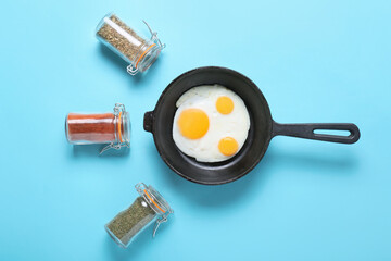 Frying pan with tasty eggs on color background