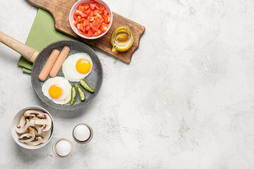 Frying pan with tasty eggs, sausages and pepper on table