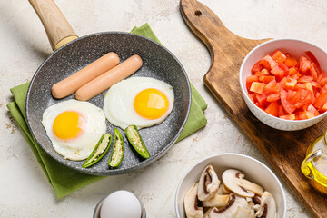 Frying pan with tasty eggs, sausages and pepper on table
