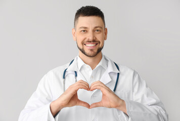 Cardiologist making heart with his hands on light background