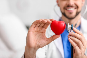Cardiologist with red heart and stethoscope in clinic, closeup