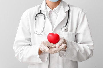 Cardiologist with red heart on light background