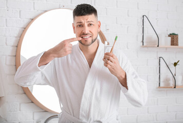 Man suffering from pain while brushing teeth in morning