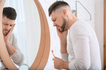 Man suffering from pain while brushing teeth in morning