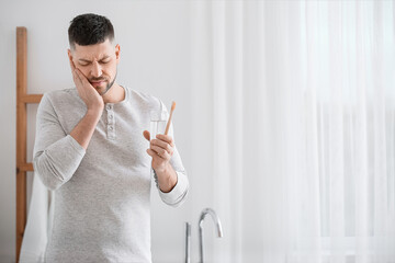 Man suffering from pain while brushing teeth in morning