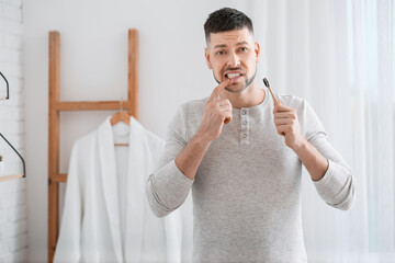 Man suffering from pain while brushing teeth in morning