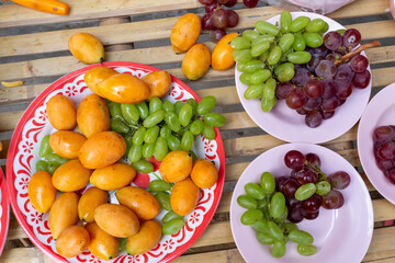 Fruits in green grapes and purple plates look delicious and have Sweet Yellow Marian Plum.