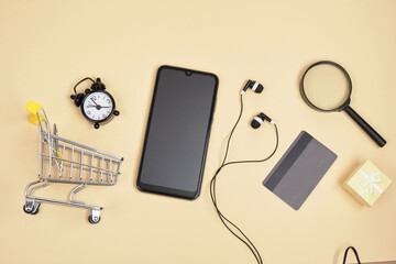 Online shopping concept. Smartphone with credit card. headphones, magnifier, alarm clock