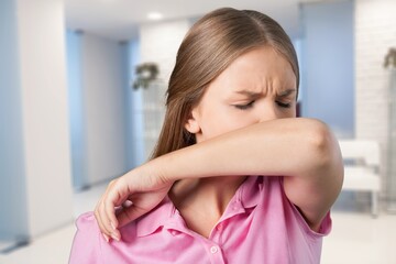 Young woman scratching her nose with elbow on background