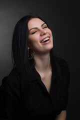 Fototapeta premium Studio portrait of a brunette in black clothes on a dark background