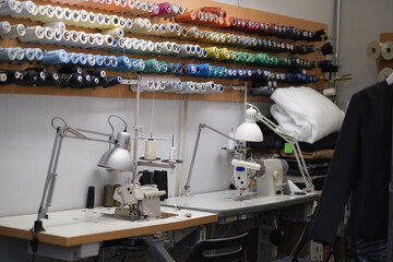 Shot of seamstress workplace. Fashion Design Studio. Sewing Machine and Various Sewing Related Items on the Table, Mannequins Standing, Colorful Fabrics.