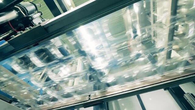 Small plastic containers moving along the production line. Bottom view