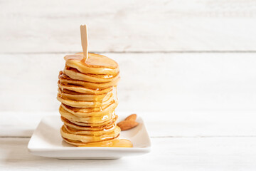 Pancakes with honey and almond on white background with copy space. Breakfast ideas.