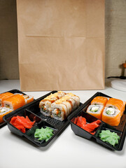 Delicious sushi rolls are served in plastic packaging on an isolated white table background.