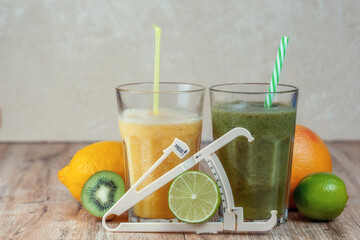 Tall glass with kiwi and spinach smoothie surrounded by fruits on a wooden table