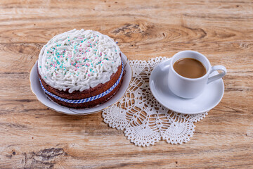 Homemade cake, decorated with white icing with decorative sprinkles and coffee