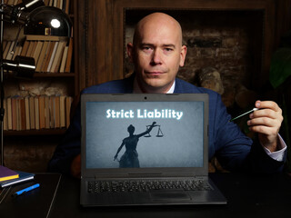 A handsome businessman showing a laptop with sign Strict Liability . Close-up shot. Soft focus.