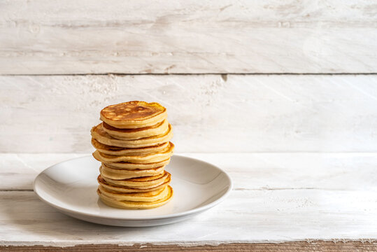 Stack of mini pancakes for Carnival of Basel, Germani Fastnacht or Fetter Dienstag on white wooden background with copy space.
