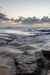 Fototapeta na wymiar Dawn view of rocky beach coastline.