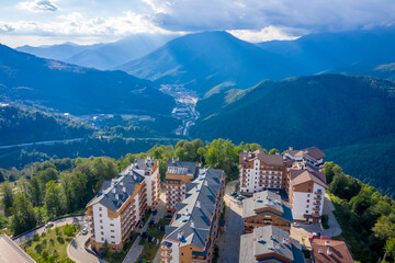 Fototapeta na wymiar Summer aerial view of the Ski Resort Rosa Khutor. A complex of hotels on the site of the former Olympic village of Rosa Plateau at an altitude of 1170 m from sea level. Krasnaya Polyana, Sochi, Russia
