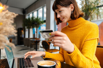 Happy young woman shopping online with credit card