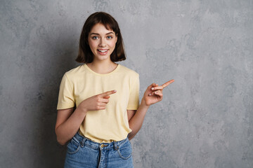 Cheerful young woman pointing fingers away at copy space