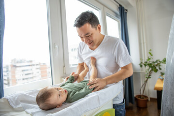 Father changing diapers to his newborn son