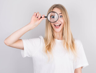 Close up portrait of cheerful beautiful girl looking through magnifying glass isolated on white background