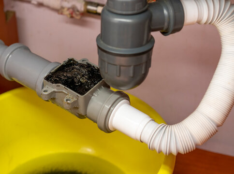 Plumbing, kitchen check valve clogged, yellow basin and debris clogging up the pipe