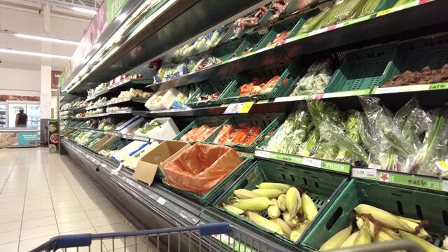 View from the shopping cart, a woman buying vegetable in Tesco Lotus store. Footage may contain noise due to low light