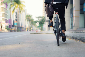 Close up of foot businessman is riding a bicycle on the city streets for his morning commute to work. Eco Transportation Concept..