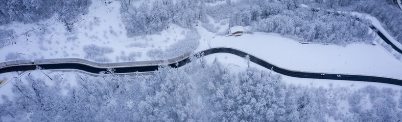 Winter aerial view of the Ski Resort Rosa Khutor and the mountain road to it. Beautiful winter landscape with frost-covered trees. Krasnaya Polyana, Sochi, Russia