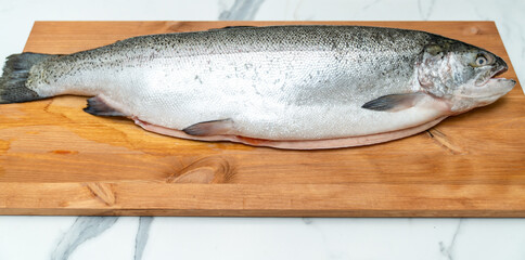 gutted trout carcass lies on a wooden board for cutting fish