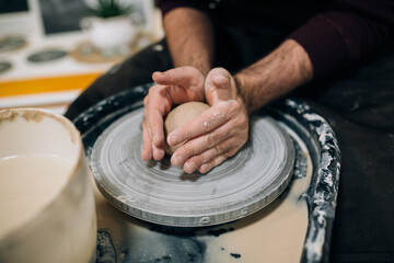 Man sculptor creating ceramics using wheel in a pottery using potter wheel