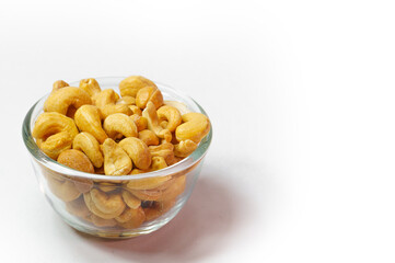 Cashew nuts in clear glass cup on white background