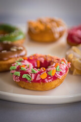 Colorful Glazed Doughnuts with Sprinkles. Served on a White Plate