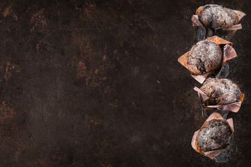 Chocolate muffins or cupcakes on brown background. Copy space.