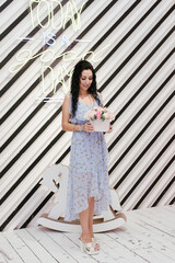Fototapeta premium slender brunette in a blue dress stands with a bouquet of flowers