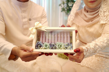 Malaysia Indonesia bride and groom holding together a set roll ringgit malaysian money inside a light wooden box