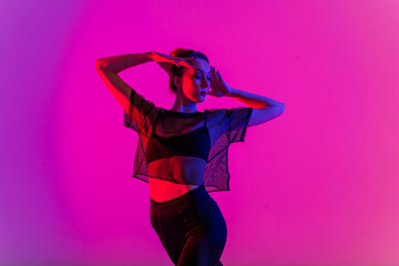 Beautiful young woman wearing sexy high heels and black clothes while dancing in pole dance studio