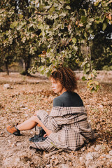 Nice girl with curly hair under an oak tree. Spring, autumn. Blue sky with clouds. 