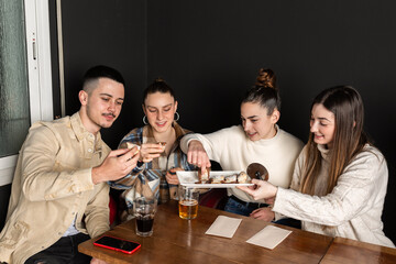 group of friends share and eat chocolate cream desserts