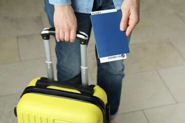 Woman hold suitcase and passport with ticket and COVID - 19 mark