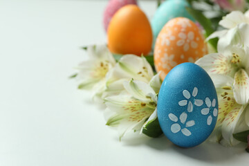 Color Easter eggs and alstroemeria flowers on white background, close up