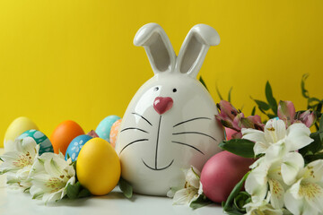 Easter bunny, eggs and alstroemeria flowers against yellow background