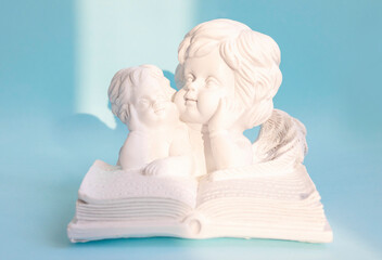 angels mom and baby bent over a book on a blue background, the concept of education and motherhood