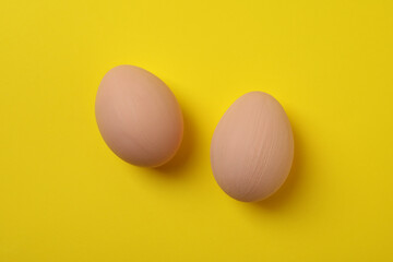 Beautiful beige Easter eggs on yellow background