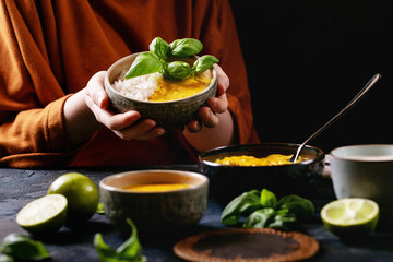 Female holding ceramic bowl of yellow curry