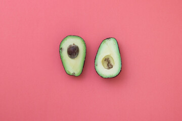 Composition of natural avocados with stone on pink background