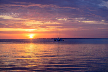 Boat on the sea. Sailboats at sunset. Ocean yacht sailing along water.